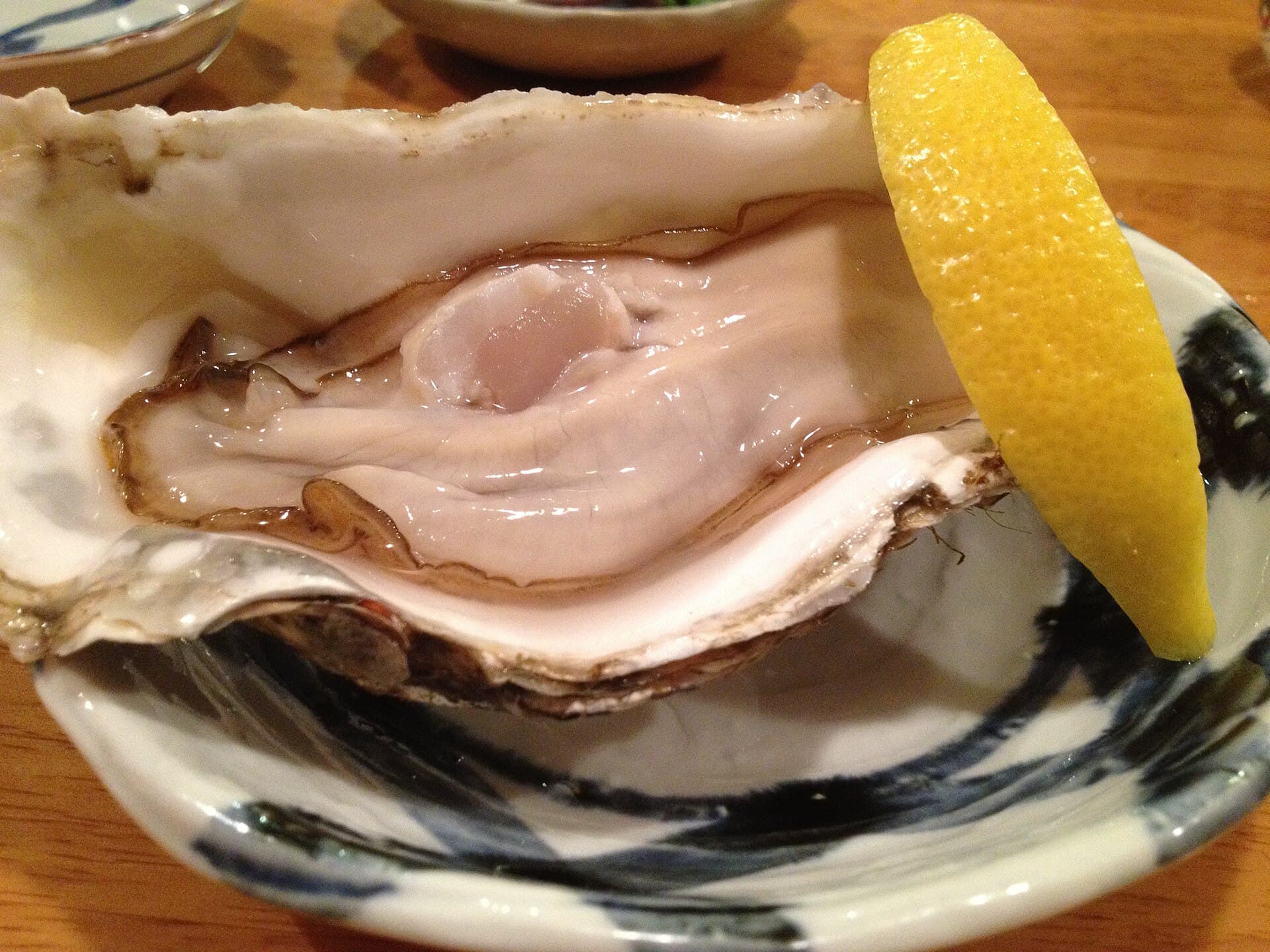 A raw oyster with a lemon wedge